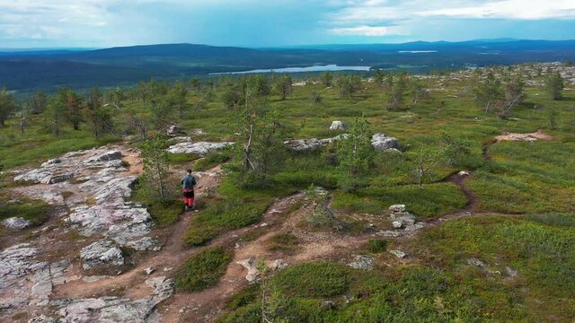 Aerial drone view of a person walking on a tunturi mountain, sunny day, in Lapland