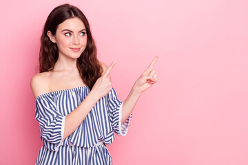 Photo of nice optimistic brunette lady point empty space wear blue dress isolated on pastel pink...