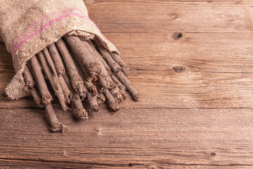 Raw Scorzonera or Spanish salsify in a sackcloth bag on vintage wooden table