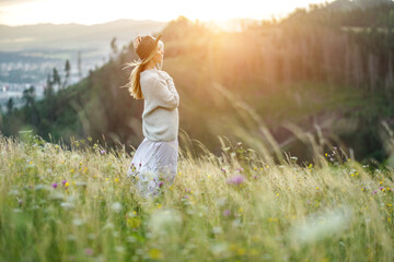 Fototapeta na wymiar happy woman enjoying sunset stay on the green grass on the forest peak of mountain. Fresh air, Travel, Summer, Fall, Holidays, Journey, Trip, Lifestyle.