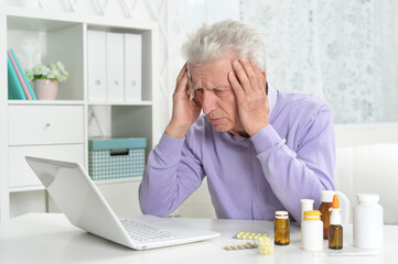 Portrait of sad sick senior man using laptop