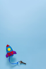 Flying up felt rocket toy with a key on a string on a blue background. The creative concept of children's education, opening up new horizons.