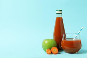 Bottle and glass of juice and ingredients on blue background