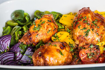 Close up of baked  chicken with vegetables in oven dish, gray background. Comfort food concept.