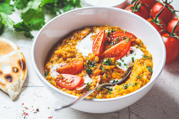 Vegan lentil soup with cilantro and tomato. Dal soup with tomatoes. Indian cuisine concept.