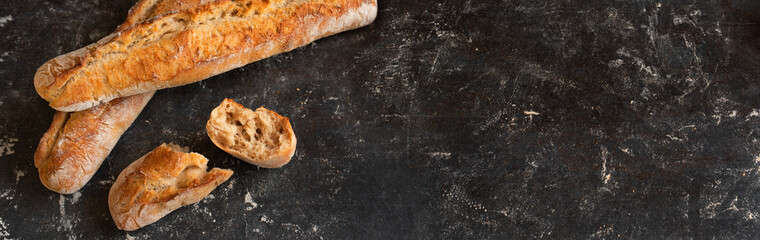 Fresh crispy french baguette on black background. Atmosphäric food photography with space for text.