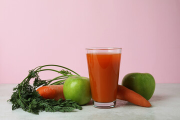 Glass of juice and ingredients against pink background