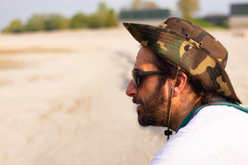 Hippy man with hat beard and glasses at the beach outdoors
