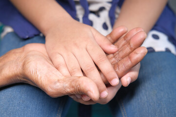 close up of child hand holding senior women's hand 