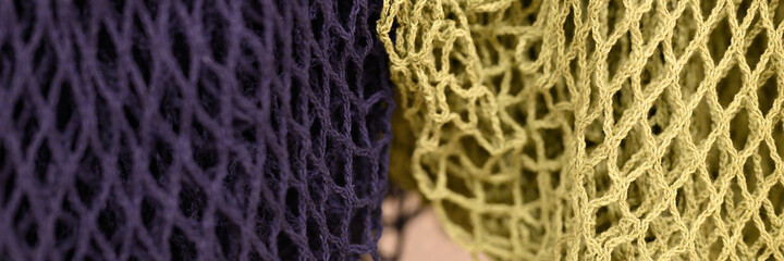 reusable shopping mesh bags purple and yellow colors close up. banner