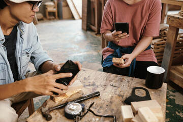 Carpenter phototgraphing wooden blocks for social media when having short coffee break in workshop