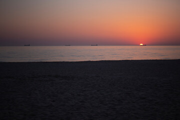 orange sunrise at sea with the silhouette of the container ship