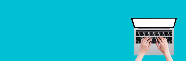 Woman&rsquo;s hands working on laptop on blue background. Office desktop. Banner