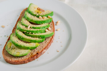 Healthy avocado toast with rye bread, sliced avocado,seeds, salt and pepper. Vegetarian food. Plant-based diet. Clean eating. Copy space.