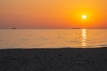 orange sunrise at sea with the silhouette of the container ship