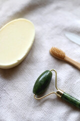 Jade face roller, wooden toothbrush, glass nail file and bar of soap. Sustainable body care products. Selective focus.