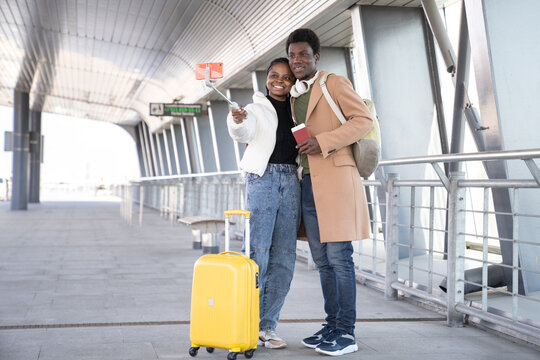 Black couple ready for trip after end of corona take selfie at airport terminal happy smile and embrace. Young man and woman travel together on honeymoon vacation, wait for departure make self photo
