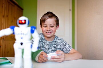 cool boy with green arm cast is sitting in his room and is playing with toy robot and is happy