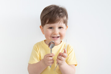 Happy boy holding a spoon and a fork