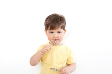 A little boy holds a fork in one hand and a spoon in the other, which he brought to his closed mouth