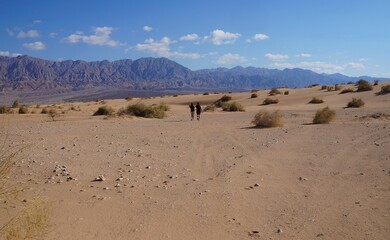 Fototapeta na wymiar Young beautiful couple enjoys their hiking in the wild desert