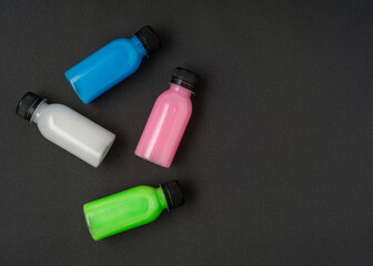 Colorful liquid in a bottles on black background. Flat lay. Copy space.