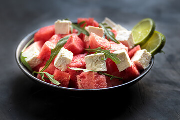 Watermelon salad with feta cheese, arugula, lime in bowl. natural helthy cuisine, fresh and tasty vegetable lunch. Mediterranian eating, cool dinner in plate without meat
