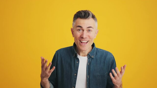 A surprised man with a smile on his face saying what while standing in the studio