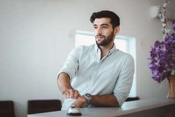 Fototapeta premium Business man using service bell on hotel reception desk.