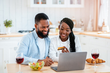 Black Couple Making Online Shopping With Laptop And Credit Card In Kitchen