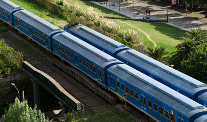 two trains crossing over the tracks, passing through the city of Buenos Aires