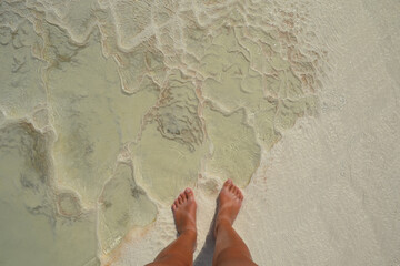 Women foots on Pamukkale Hot Springs close-up texture, detail of travertine cascades  background. Abstract texture of salt mineral springs