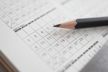 Sharp black pencil lying on calendar closeup