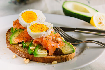 Healthy avocado toast with rye bread, salmon,seeds and egg on a plate