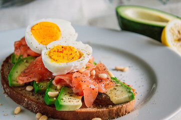 Healthy avocado toast with rye bread, salmon,seeds and egg on a plate