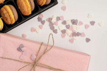 gift box on a white background decorated with delicate candy hearts and a stylish dessert macarons