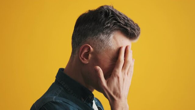 A side-view of a pensive mature man regretting done while standing in the studio