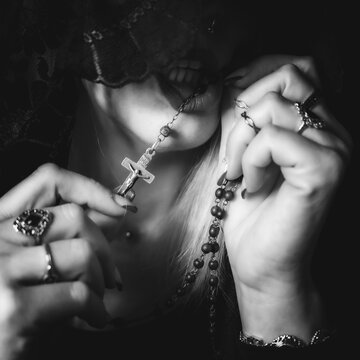 mujer sin rostro moderna rezando con mantilla anillos y un rosario