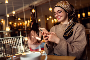 Portrait of young woman working on using laptop at coffee shop.