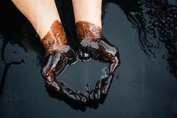 Caucasian oil hands are folded in a bowl of oil. Oil spill. Environmental pollution. an...