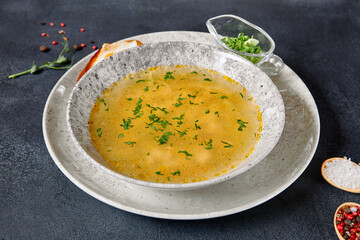 Traditional Bowl Food - Chicken Noodle Soup on Dark Table. Soup in ceramic bowl on dark textured background with food ingredients.