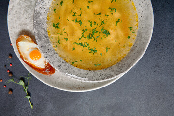 Traditional Bowl Food - Chicken Noodle Soup on Dark Table. Soup in ceramic bowl on dark textured background with food ingredients.