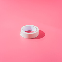 White roll of scotch tape on a pink background in a minimalist style