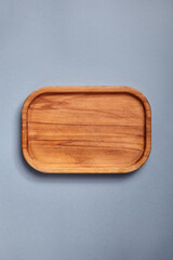 Empty wooden tray on textured dark blue table. Rectangular wooden dish top view. Kitchen minimal...