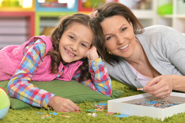 Fototapeta premium Mother with little daughter collecting puzzle