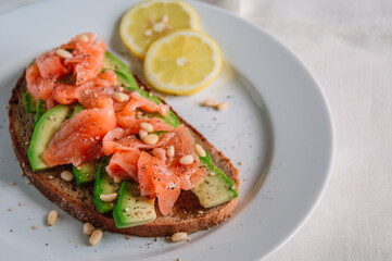 Healthy avocado toast with rye bread, sliced avocado,salmon,seeds, salt and pepper. Vegetarian food. Clean eating.