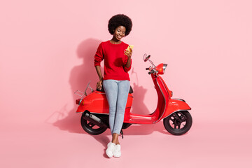 Fototapeta na wymiar Full size photo of dark skin person sitting on moped look phone typing blog post isolated on pink color background