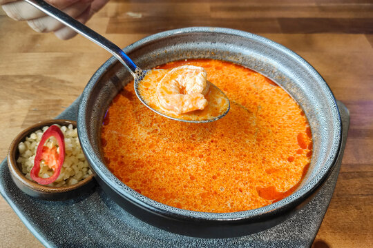 Bowl wuth a hot delicious tom yum soup and a spoone with a shrimp.