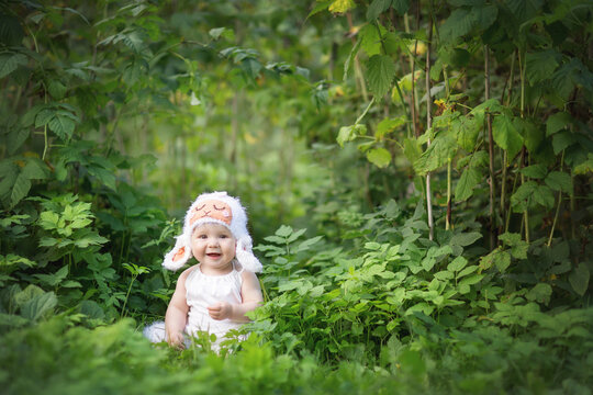 baby in the dress of a sheep in the summer in the garden in the grass