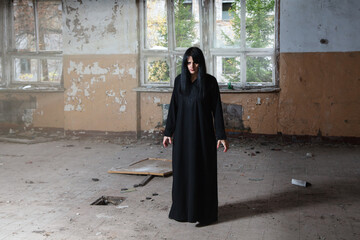 young goth woman standing in room of abandoned house